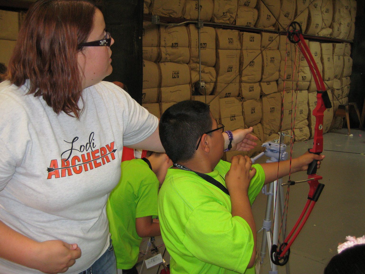 A woman shows a young boy who is visually impaired how to hold a bow. A woman shows a young boy who is visually impaired how to hold a bow.