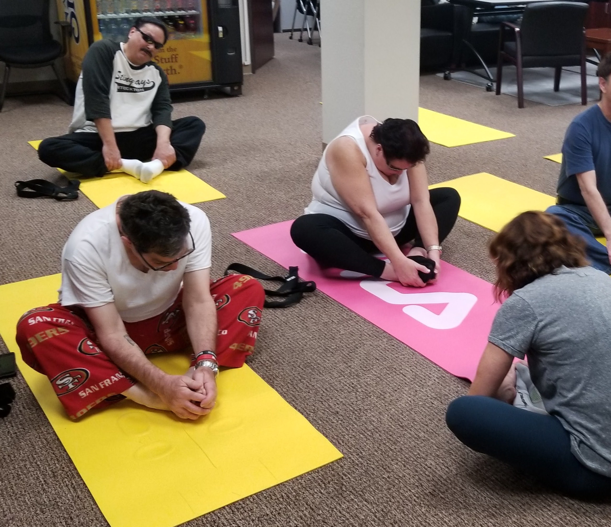 Two male and one female client perform seated yoga movements.