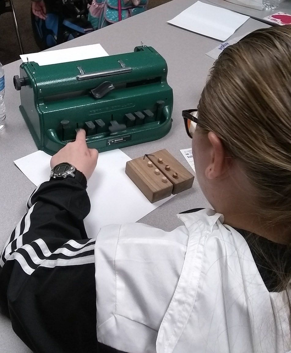 A student learns the braille cell using a swing cell and to write with a brailler.